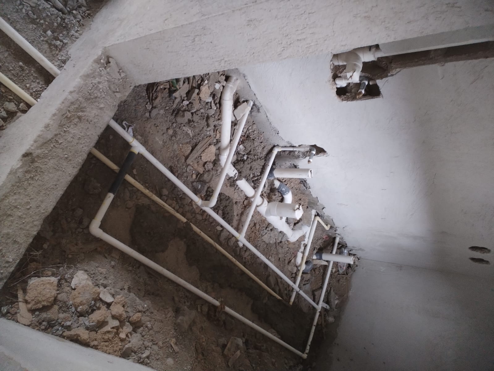 Red de plomería expuesta durante apertura de piso y muro